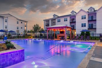 A swimming pool with a lit-up gazebo in the background.